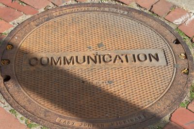 A manhole cover with the word “Communication” stamped into the steel
